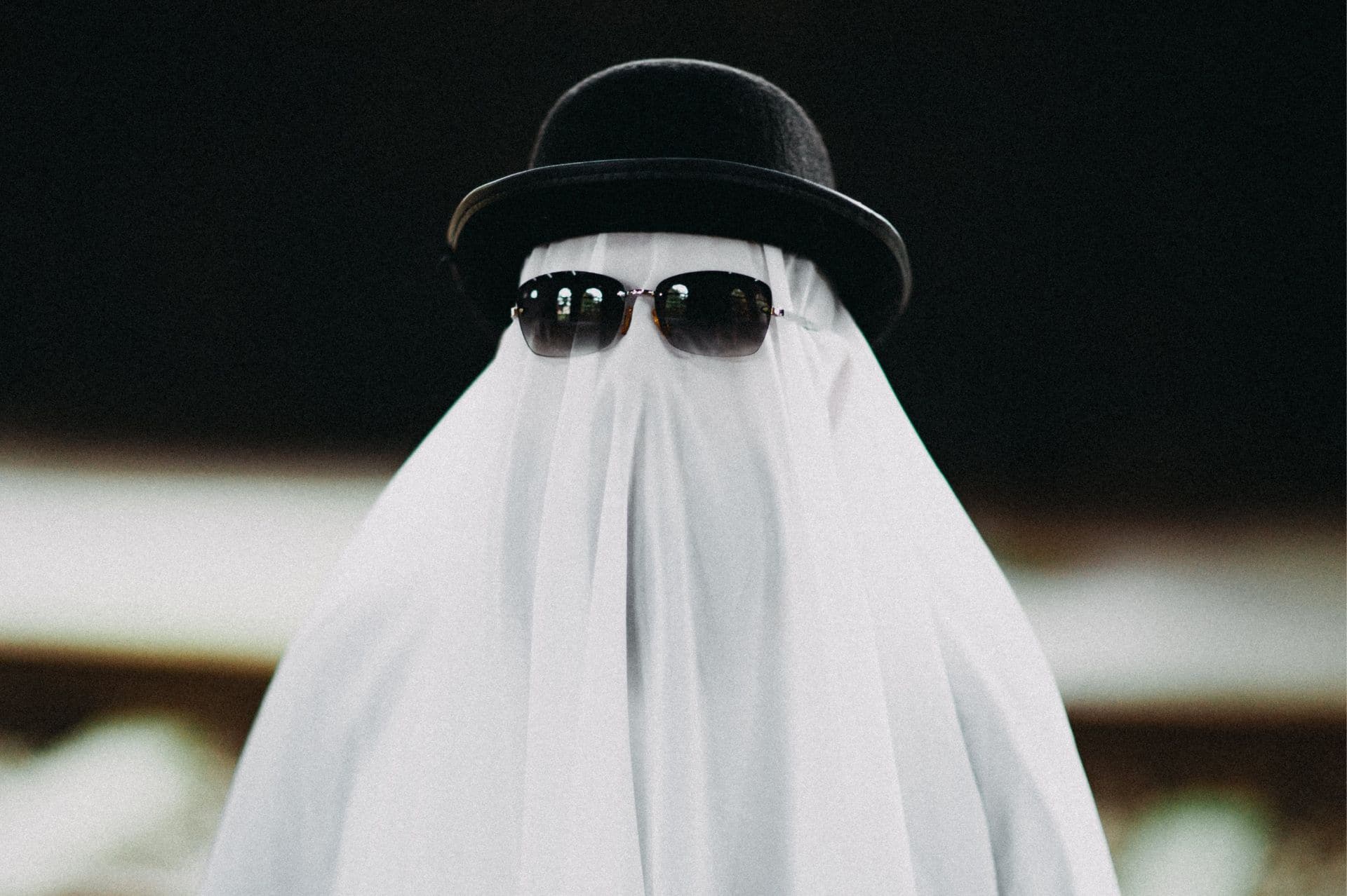 A person dressed as a ghost with a white sheet, sunglasses, and a hat, symbolizing emotional detachment and the fear of showing true feelings — a visual metaphor for “ghosting” and avoiding vulnerability in relationships.